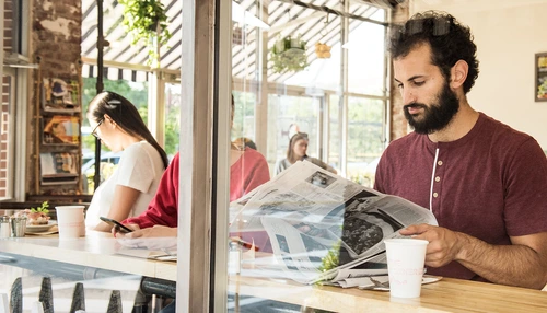 Man reading newspaper in cafe