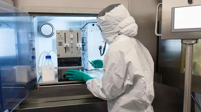 Een medewerker in volledige beschermingsuitrusting die gespecialiseerde apparatuur gebruikt op de RLT-productielijn 