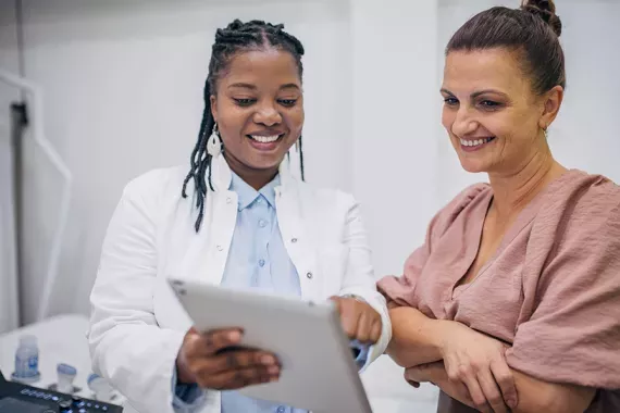 A doctor and a patient discussing medical results on a tablet