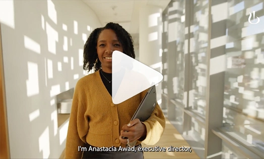 Eine junge Frau posiert mit ihrem Computer in einem hellen Flur