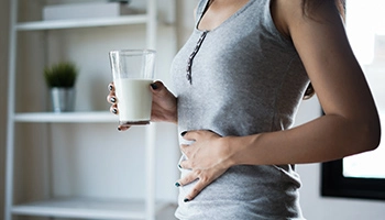 Eine Frau trinkt ein Glas Milch und achtet dabei auf die Wirkung