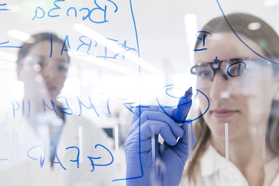 Wissenschaftlerin schreibt an einer Glaswand