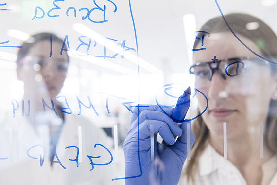 Scientifique écrivant sur une surface vitrée
