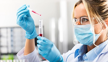 Une employée de laboratoire manipule une pipette et un tube à essais