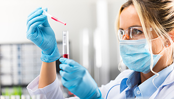 Eine Labormitarbeiterin hält eine Pipette und ein Reagenzglas in der Hand