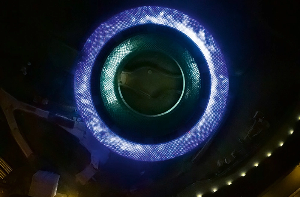 Blick von oben auf den erleuchteten Novartis Pavillon nach Einbruch der Dunkelheit. / Vue du dessus sur le Pavillon Novartis éclairé après le crépuscule.