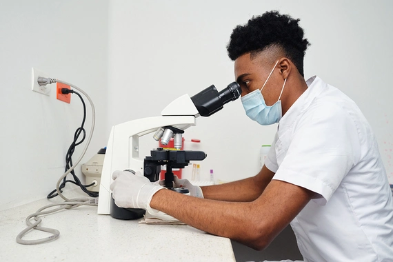 Ein Laborant untersucht eine Probe unter einem Mikroskop