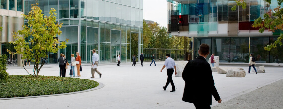 Courtyard of a modern Novartis corporate campus with glass buildings and walking pedestrians