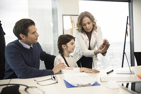 lékařka vysvětluje dětské pacientce jak používat inhalátor
