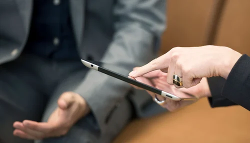 Hände, die ein Tablet halten und etwas zeigen