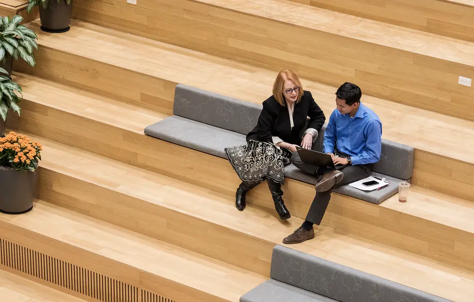 Kolleg*innen sitzen auf der Treppe am Laptop