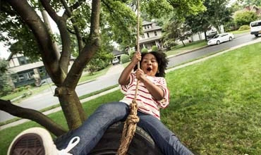 Junger Mensch auf einer Schaukel im Baum