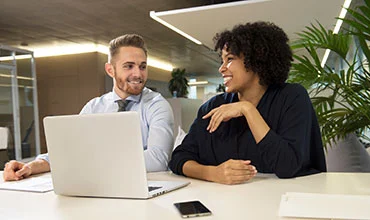 Zwei Kolleg*innen bei der Arbeit am Laptop