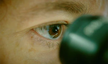 Nahaufnahme einer Person, die in ein Mikroskop blickt.