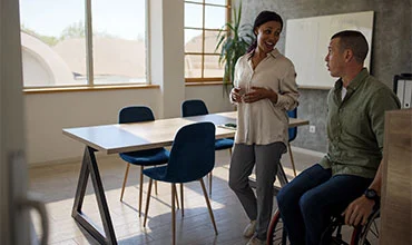Zwei Personen im Gespräch in einem modernen Büro.