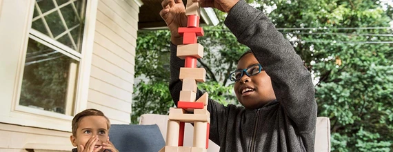 Zwei Kinder bauen einen Turm aus Holzklötzchen
