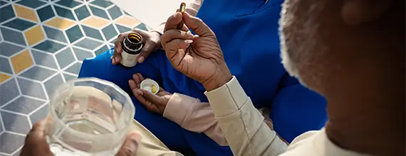 Medizinisches Fachpersonal verabreicht einem Patienten ein Medikament zum Einnehmen