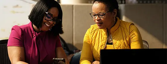 Zwei Kollegen diskutieren über einen Laptop und ein Telefon
