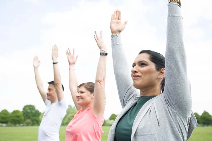 Drei Personen machen im Park zusammen Yoga