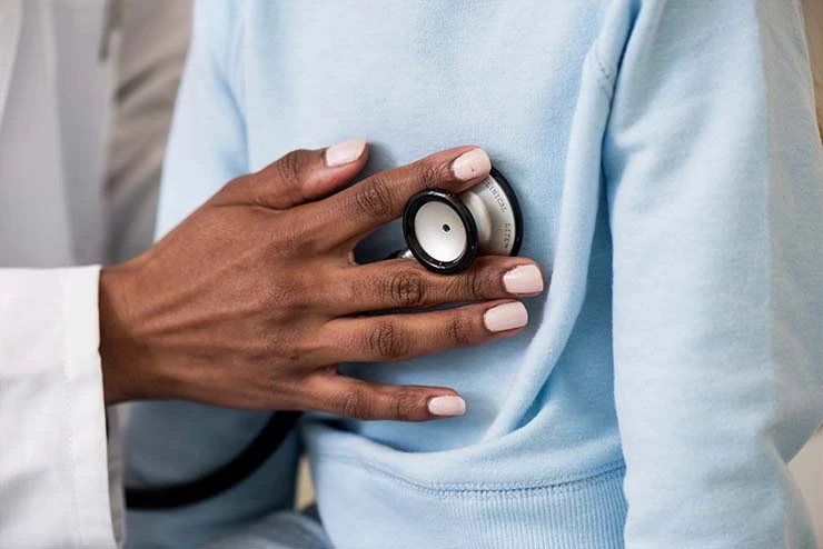 Ein Arzt untersucht mit einem Stethoskop einen Patienten