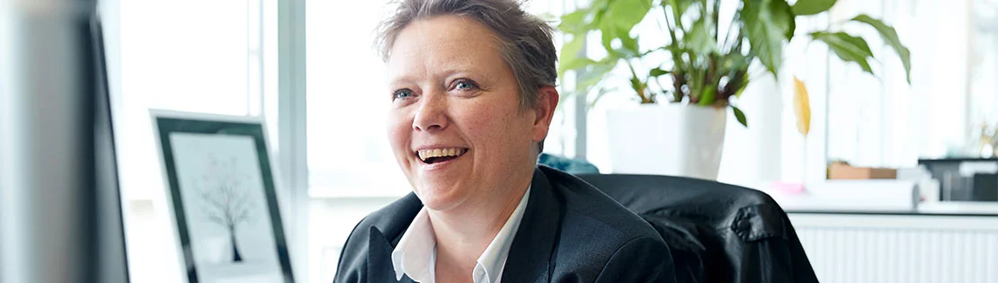 Eine Glückliche Mitarbeiterin schaut in Richtung der Kamera