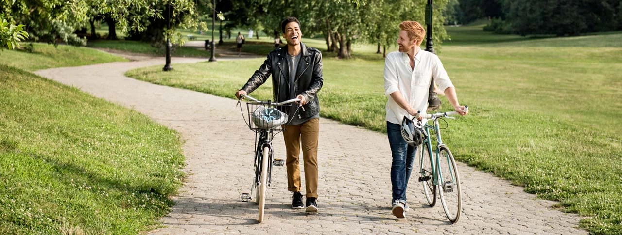 Zwei Männer schieben ihre Fahrräder durch den Park