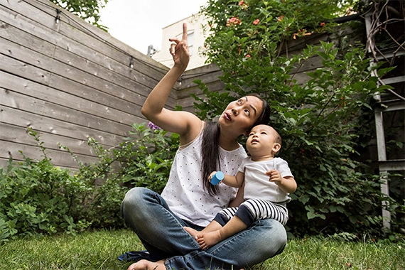 Eine Mutter sitzt mit Baby im Garten