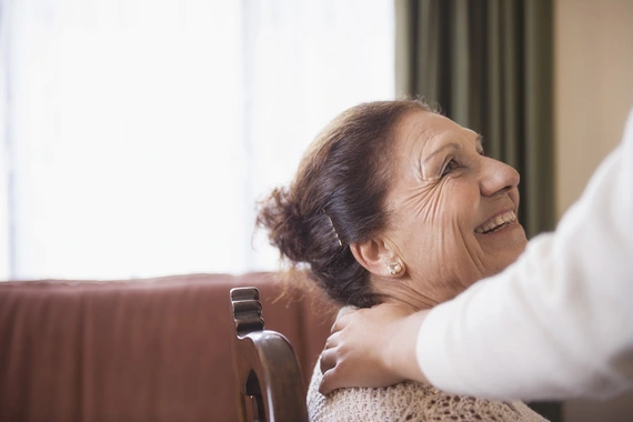 Eine fröhliche Frau wird von einer Bekannten begrüßt