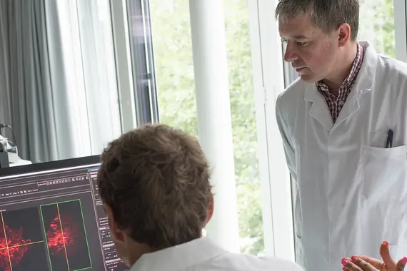 3 Wissenschaftler*Innen diskutieren vor Bildschirm