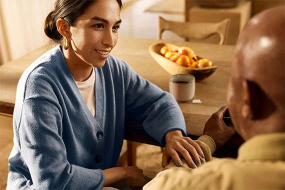 Älterer Erwachsener und Pflegekraft führen zu Hause ein tröstliches Gespräch.