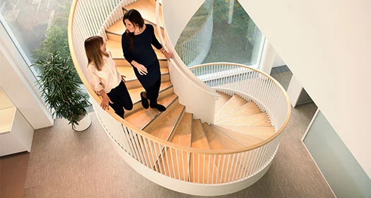Kollegen gehen auf einer modernen Wendeltreppe.