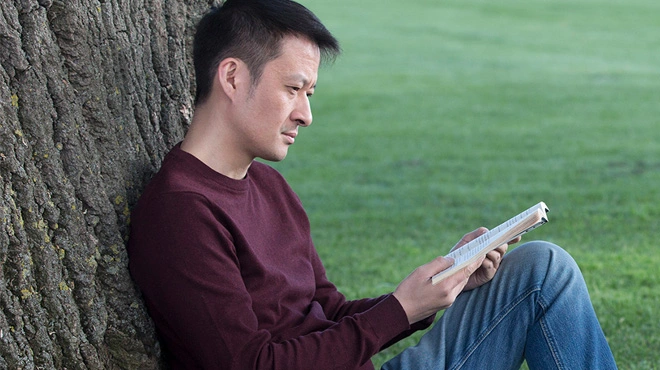 mann liesst unter einem baum klein