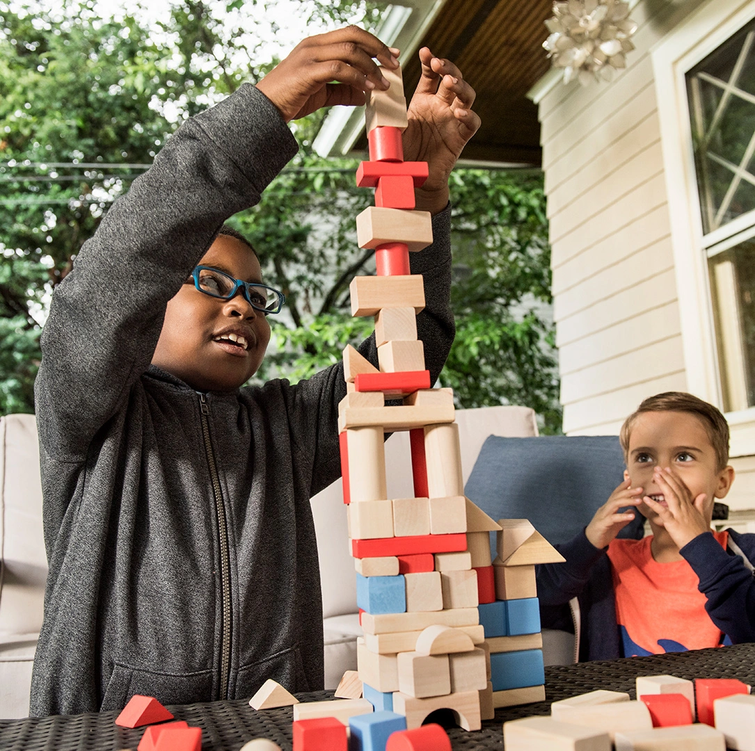 Zwei Kinder bauen einen Turm aus Holzklötzchen