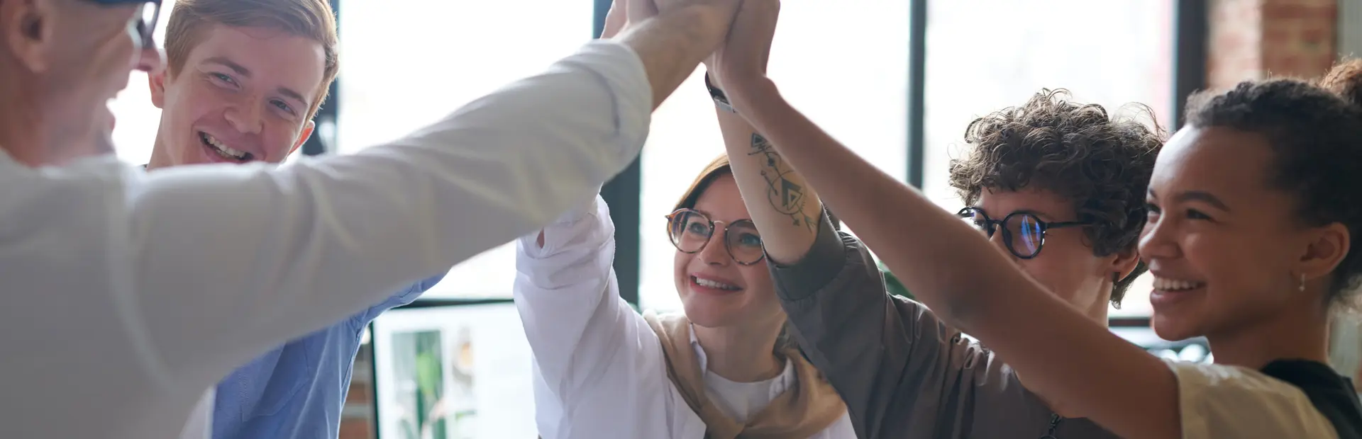 Jóvenes chocando las manos en lo alto con su profesor 