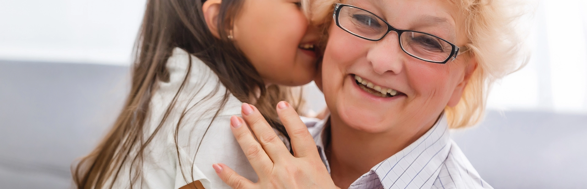 mujer mayor abrazando a niña pequeña y sonriendo