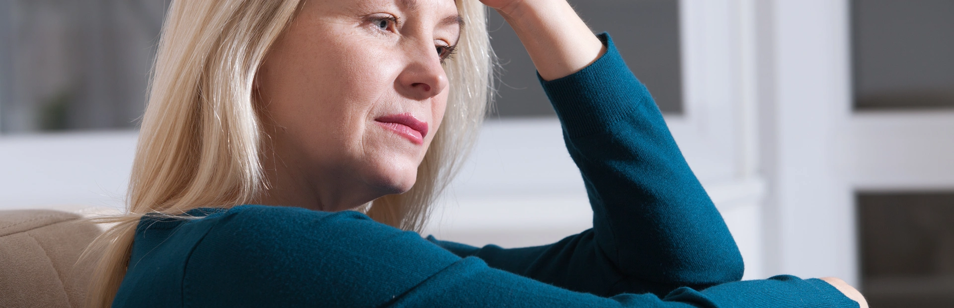 Mujer rubia acariciándose con preocupación la cabeza 