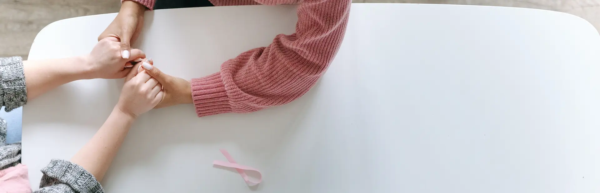 Paciente con cáncer de mama dándose la mano con una amiga