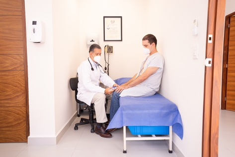 Doctor tomando la tensión a su paciente en una camilla