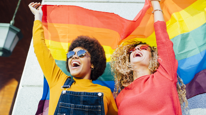 Dos mujeres ondean la bandera arcoíris