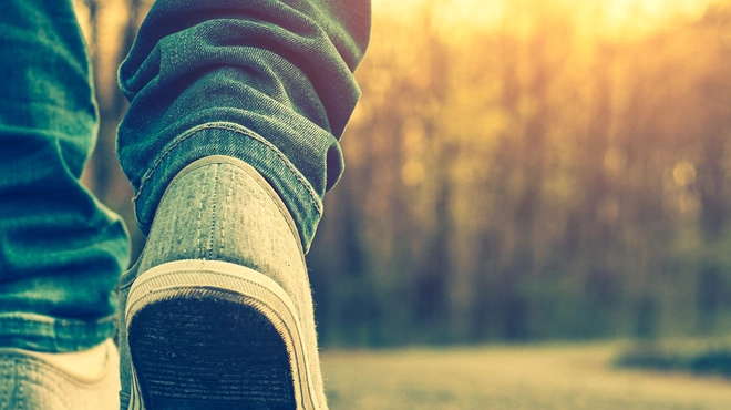 Pies caminando por un camino en el bosque