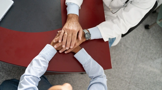 Doctor sosteniendo las manos del paciente