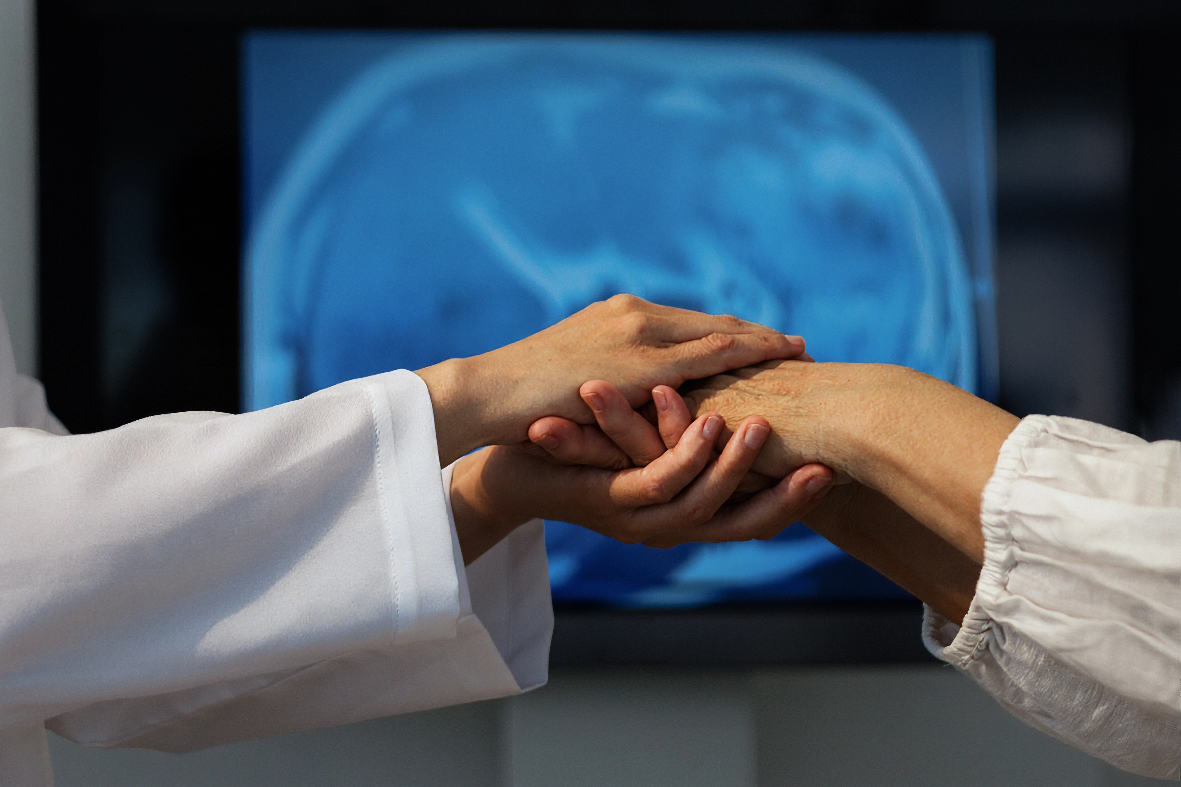 Doctors examining a patient's hand with brain scan in background