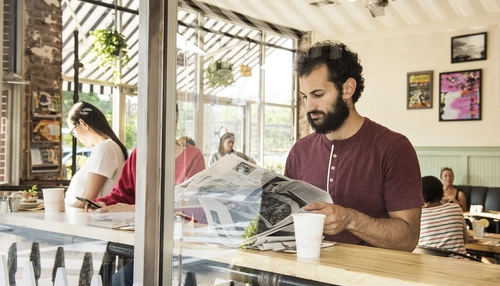 Man reading newspaper in cafe