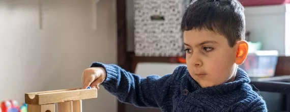 A boy playing with wooden marble runs toy