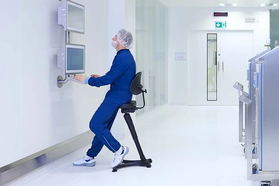 production specialist working on computer next to machine