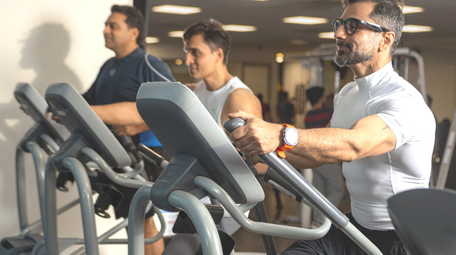 3 mannen trainen in een sportschool op een cardio fitness apparaat