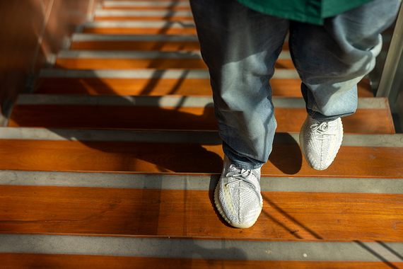 Person walking on wooden stairs indoors, shadows cast on steps below.