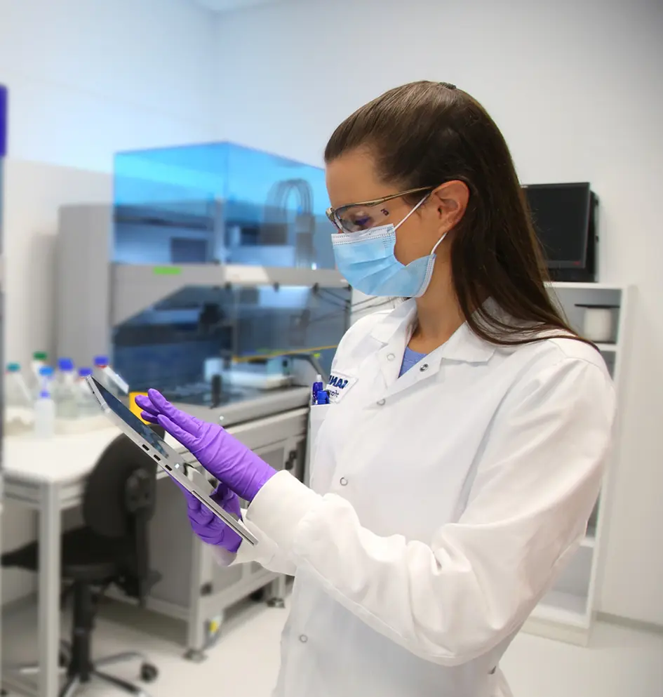 Scientist in mask and gloves using tablet in laboratory