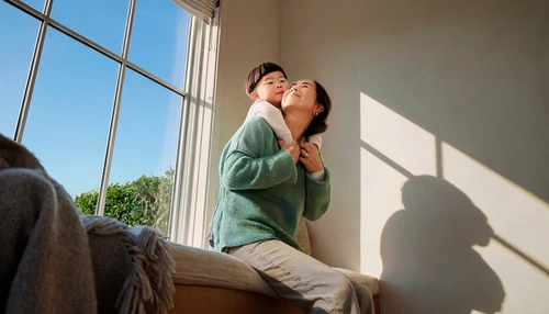 Mother and son cuddling on a couch in front of a window