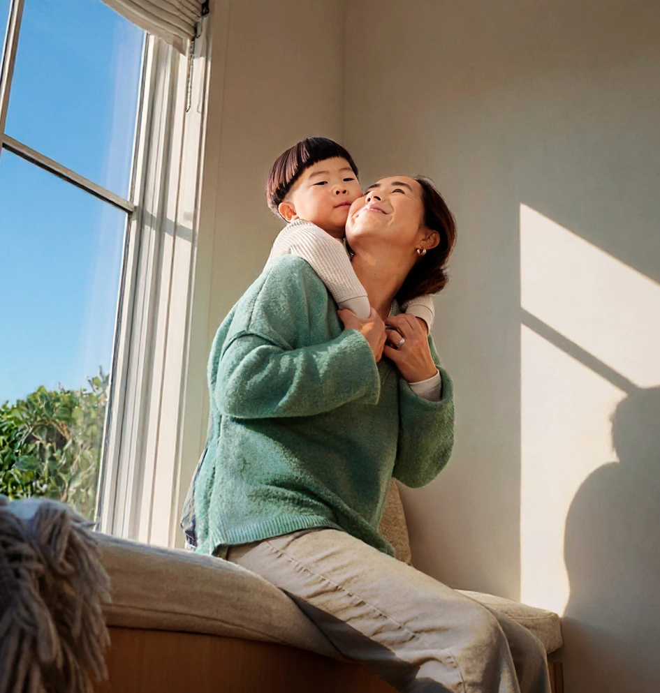 Mother and son cuddling on a couch in front of a window